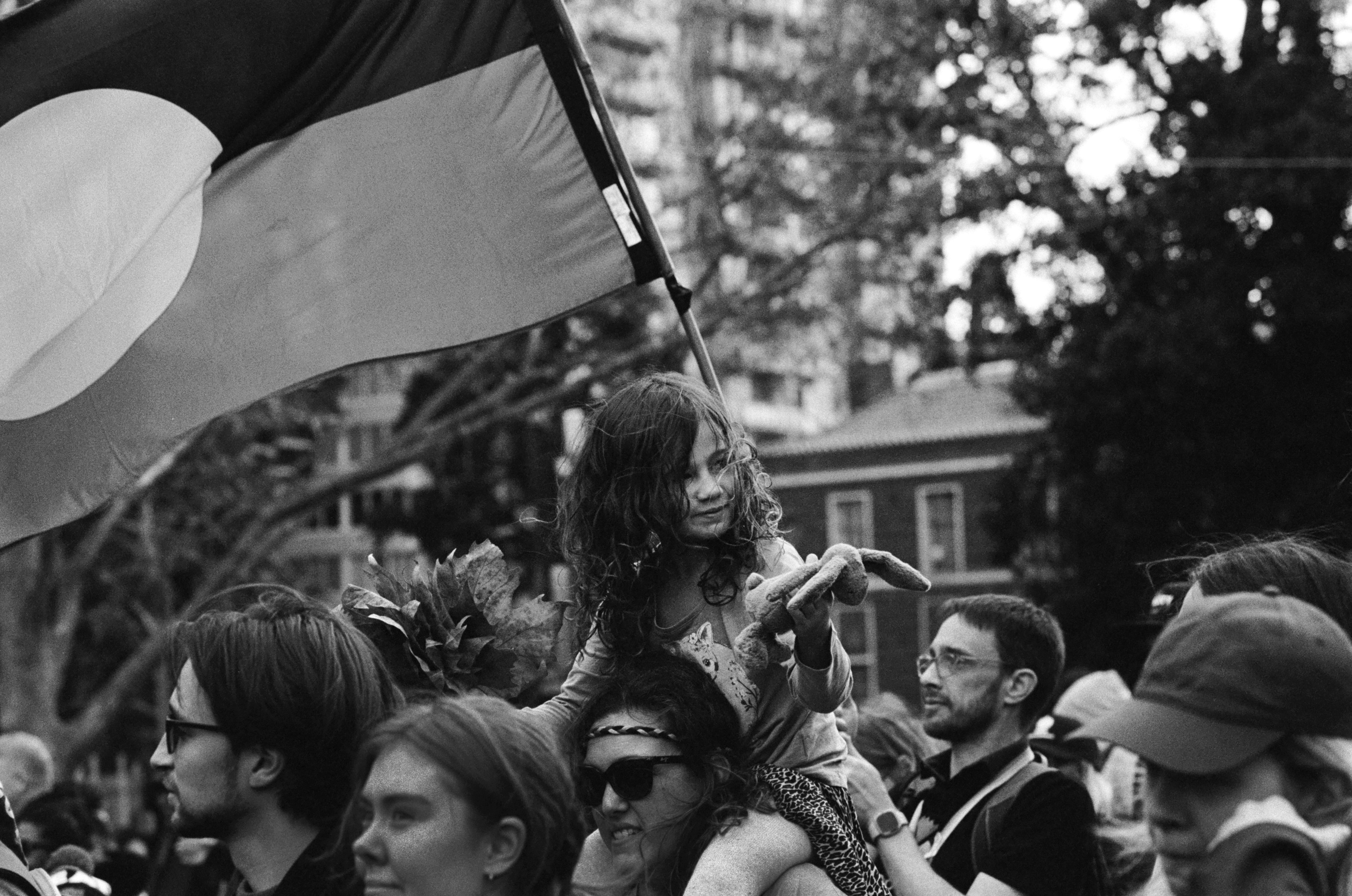 A little aborginal girl on the shoulders of a parent in a crowd